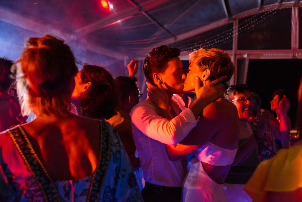 Brides kissing on the dancefloor with red and purple red lights during their Cancun Wedding Photo Taken by Citlalli Rico Photography