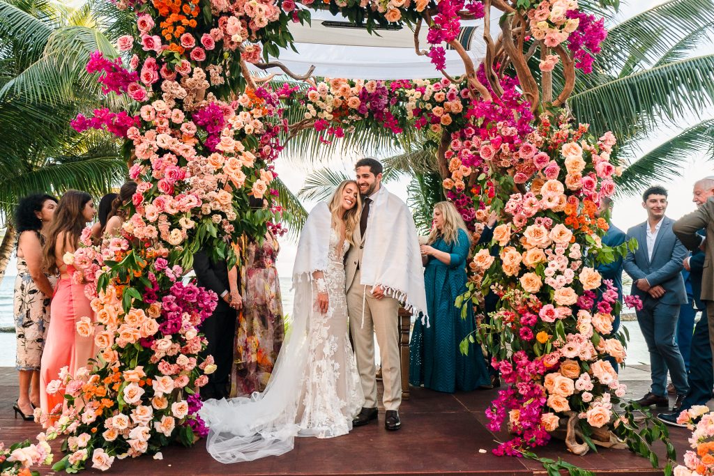 Jewish couple ceremony under an arch of flowers By the best destination wedding photographer cancun and Riviera Maya